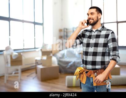 builder in helmet calling on smartphone at home Stock Photo