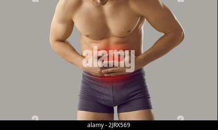 Man who suffers from digestive disorder and stomachache holding hands on his abdomen Stock Photo