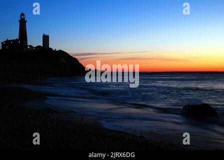 A dawn sky glows behind the Montauk Point Lighthouse, a distinct landmark of the Hamptons on the easternmost tip of Long Island Stock Photo