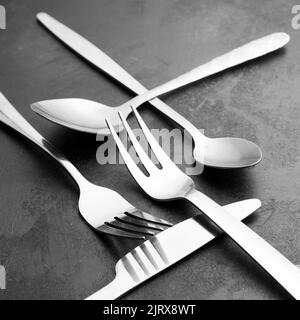 A closeup shot of silverware with forks, spoons and a knife on the black background Stock Photo