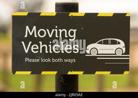 A pedestrian crossing warning sign saying 'Moving Vehicles, please look both ways' Stock Photo