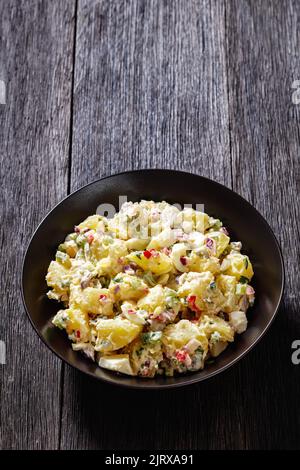 shout hallelujah potato salad with pickles, celery, eggs, jalapeno and mayonnaise dressing in black bowl, vertical view Stock Photo