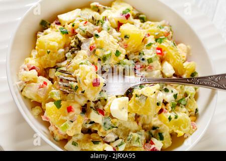 shout hallelujah potato salad with pickles, celery, eggs, jalapeno and mayonnaise dressing in white bowl, close-up Stock Photo