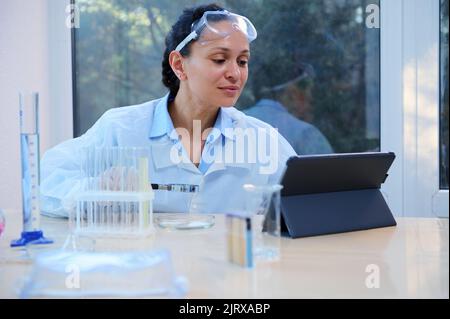 Latin American female scientist conducting experiments and analyzing the results on a tablet, in medical bio laboratory Stock Photo