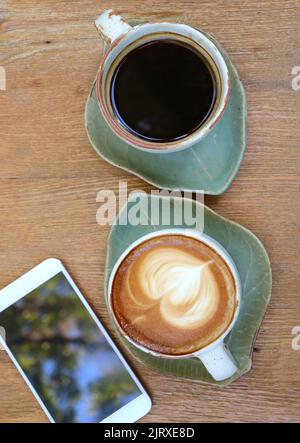 Two cups of hot coffee with blank screen smartphone on wooden table Stock Photo
