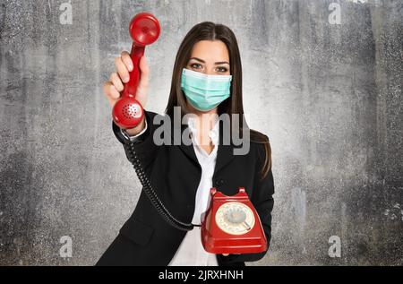 Masked businesswoman using a vintage telephone during coronavirus pandemic Stock Photo