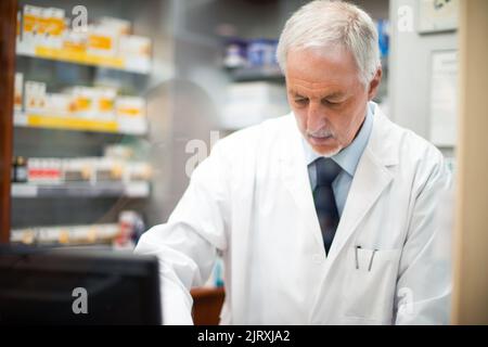 Pharmacist working behing a glass in his pharmacy Stock Photo
