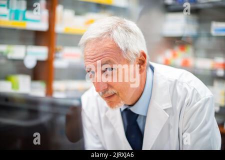 Pharmacist working behing a glass in his pharmacy Stock Photo