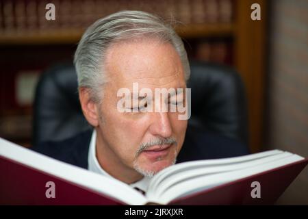 Senior business man reading a book in his library Stock Photo
