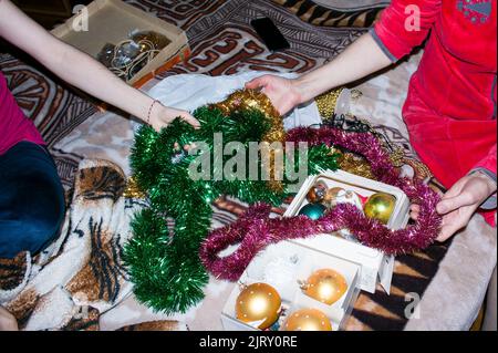 Two women are choosing Christmas decorations for the home tree. Womans hands are holding Christmas toys and garlands. Christmas mood. Christmas prepar Stock Photo