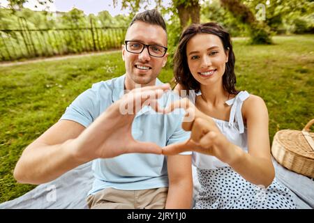 happy couple making finger heart at summer park Stock Photo