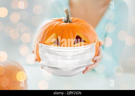 close up of woman holding pumpkin in mask Stock Photo