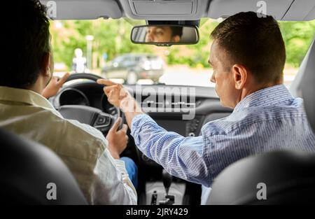 car driving school instructor teaching male driver Stock Photo