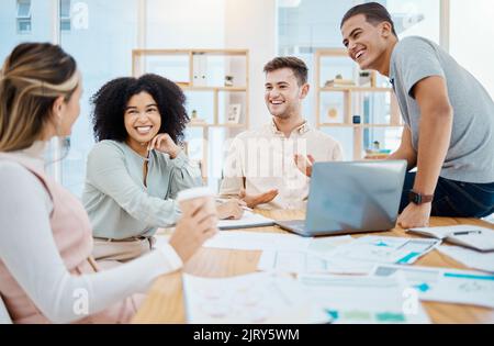 Happy business people laughing and enjoying a casual chat in an office, taking a break from paperwork. Diverse work friends bonding and talking about Stock Photo