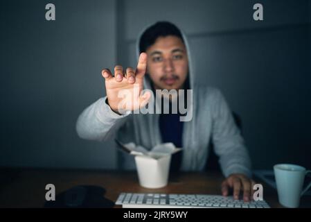 Touching the future. a young man using an unseen digital interface while sitting at a computer late at night. Stock Photo