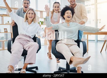 Happy corporate colleagues having fun and being playful in an office, playing a game on chairs. Laughing friends silly and goofy, bonding and enjoying Stock Photo