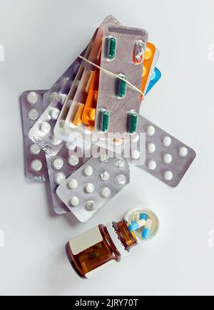 Pile of pills blisters with open glass medicine container on white background Stock Photo