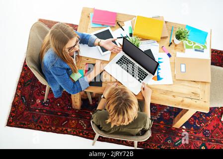 Doing some cramming in the quad. High angle shot of two female university students working on a project together at a table on campus. Stock Photo