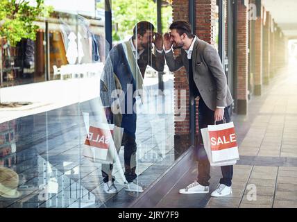 They might have what Im looking for. a man peering through a shops window while out on a shopping spree. Stock Photo
