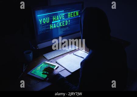 Dark deeds in the dead of night. an unidentifiable hacker using a computer late at night. Stock Photo