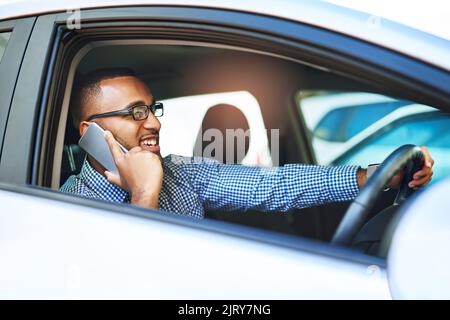 Keeping in contact during his commute. a young businessman talking on a cellphone while driving a car. Stock Photo
