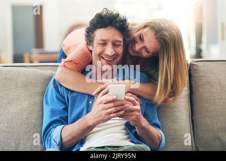 Guess who just texted. a happy mature couple using a mobile phone together at home. Stock Photo