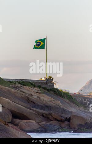 brazil flag on top of a rock at the devil's beach in rio de janeiro Brazil. Stock Photo