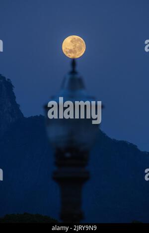 full moon setting behind a light pole early in the morning in the city of Rio de Janeiro Stock Photo