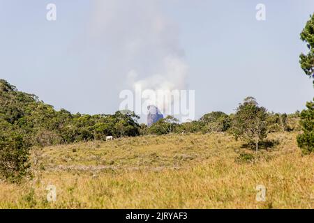 Peak summit of the friar of Angra dos reis coming out of smoke, seen from the city of Bananau in the Serra da Bocaina in Sao Paulo Brazil. Stock Photo
