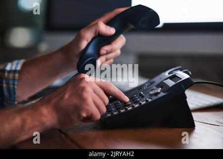 Keeping things old school. an unidentifiable businessman using a desk phone in the office. Stock Photo