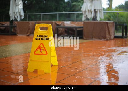 Caution wet floor yellow sign warning while it raining outside. Safety first and need to be clean. protect from injury slippery to the ground. Stock Photo