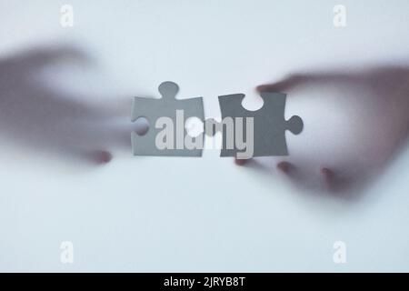 Finding the right fit for your business. Defocussed shot of two unrecognizable businesspeople holding two puzzle pieces together. Stock Photo