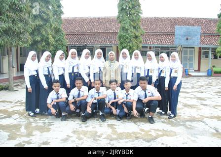 Tegal, INDONESIA, 18 Mar 2019 - A group of junior high school students and a homeroom teacher taking a photo together in a school field Stock Photo