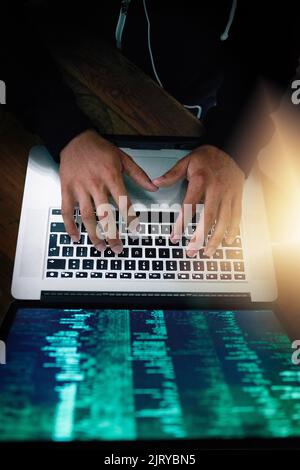 Hes the master at manipulating networks. High angle shot of a hacker cracking a computer code in the dark. Stock Photo