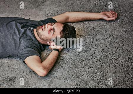 Looks like a rough night. High angle shot of a beaten and bruised young man passed out on the floor. Stock Photo