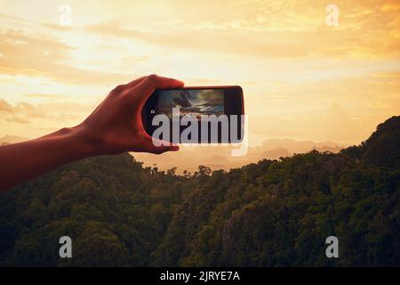 Photographing paradise. Closeup shot of an unidentifiable man taking a photo on his cellphone outside. Stock Photo