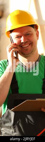 Carpenter in helmet talking on phone and taking order Stock Photo