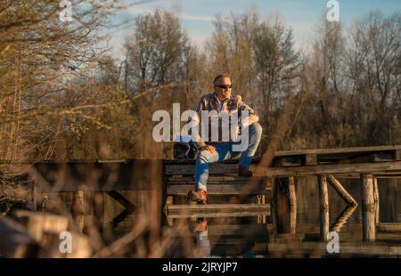 Middle-aged man sitting on a jetty by the lake, relaxing. Karlsruhe, Germany Stock Photo