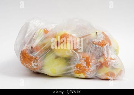 plastic bag with spoiled rotten apples on white background. Stock Photo