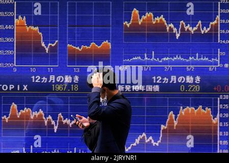 Tokyo, Japan. 24th Aug, 2022. A man wearing a protective mask, amid the COVID-19 outbreak, walks past an electronic board displaying Japan's Nikkei index outside a brokerage in Tokyo. Credit: SOPA Images Limited/Alamy Live News Stock Photo