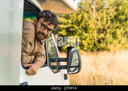 young and cheerful Caucasian man looking from the van's window. High quality photo Stock Photo