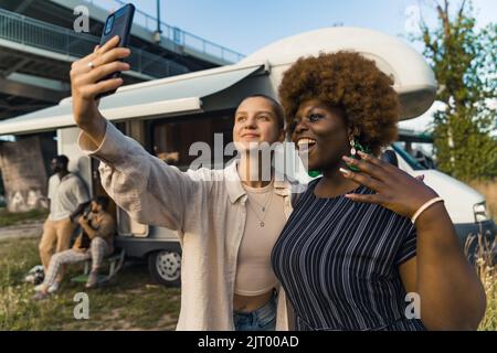 Caucasian and Afro-American friends taking a selfie with a smartphone, outdoors medium shot friendship and trip concept. High quality photo Stock Photo