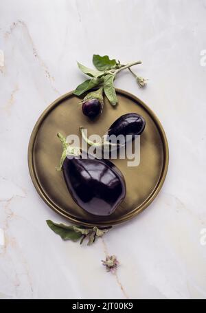 Beautiful minimalistic composition of eggplants on a round dish on a marble background. flat lay Stock Photo