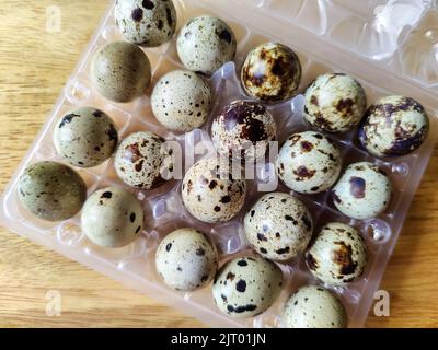 Quail eggs in their plastic packaging on wooden background. Close-up. View from above. Selective focus. Stock Photo