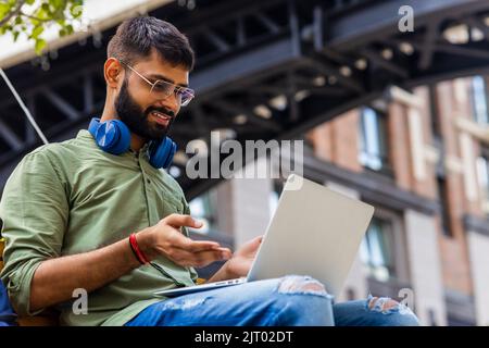 Portrait Indian student programmer using laptop computer in park Stock Photo