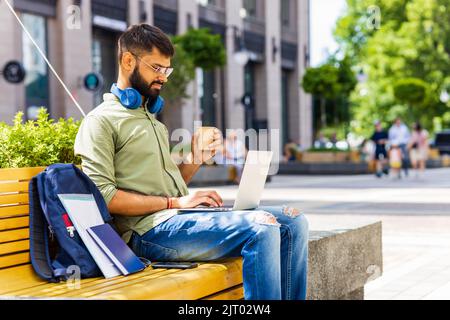 Portrait Indian student programmer using laptop computer in park Stock Photo