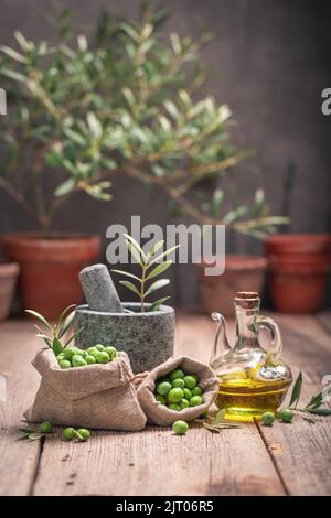 Healthy raw olives with a twig and mortar. Freshly picked green olives. Stock Photo