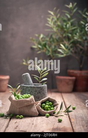 Green raw olives with a twig and mortar. Freshly picked green olives. Stock Photo