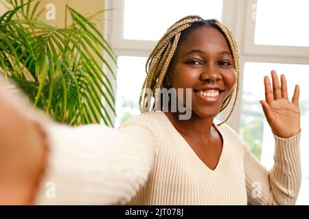 afro american woman waving hand greeting by video call at home