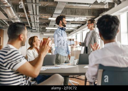 Smiling female boss leader shaking hand of new team member recruiting him for job on staff briefin Stock Photo